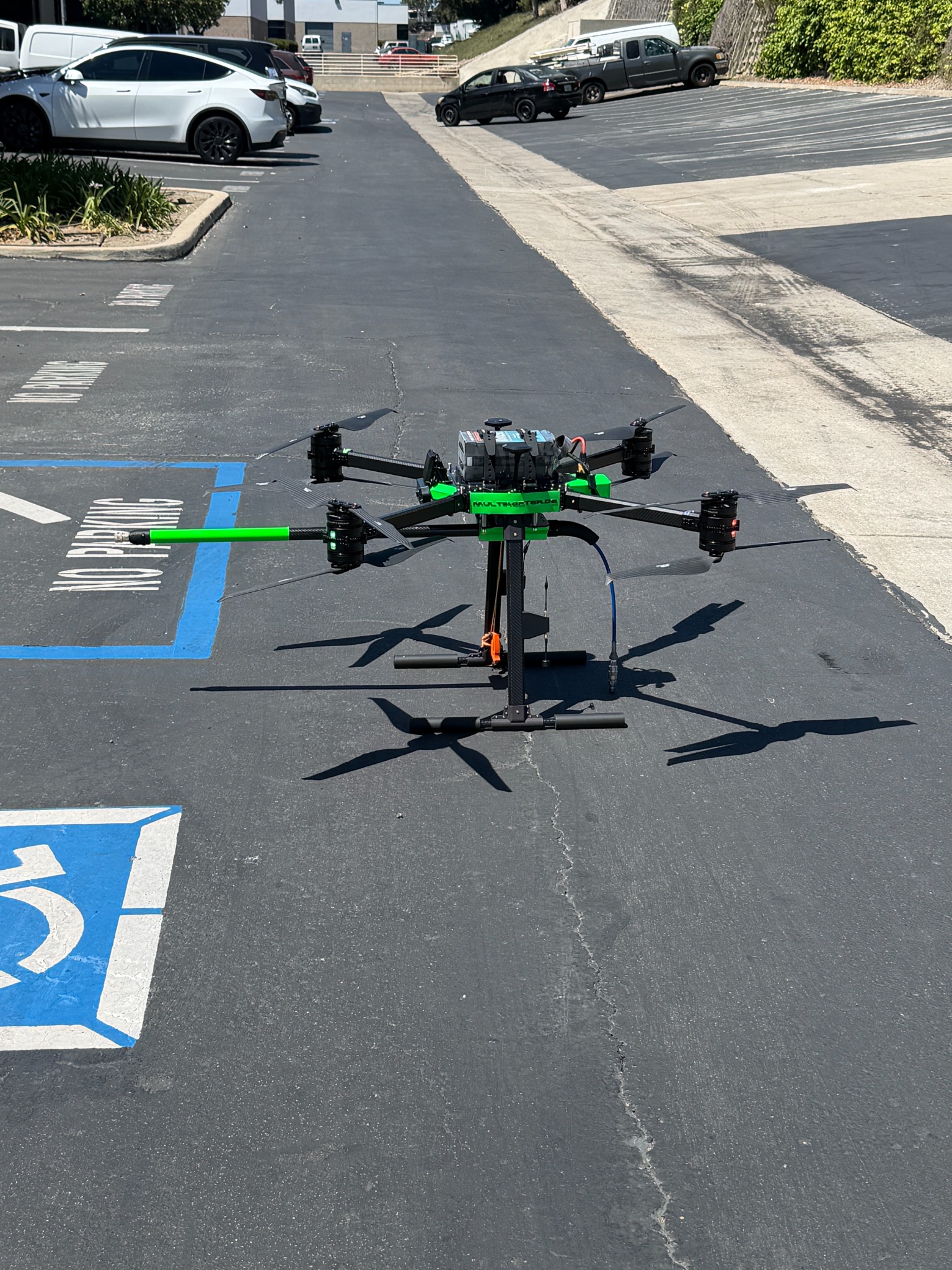 Actual eight-motor cleaning aircraft with its green spray wand on a paved surface